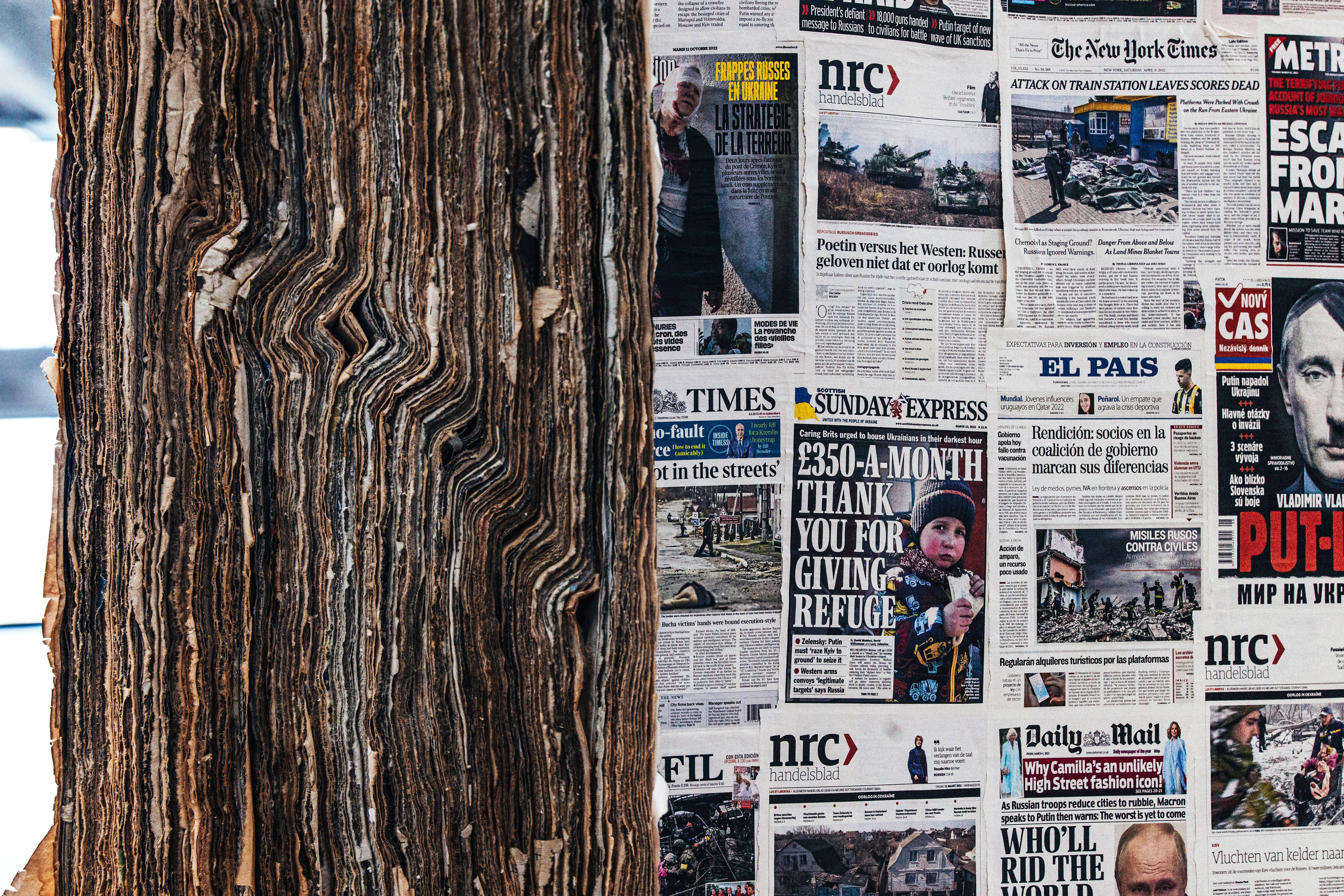 Detailed view of layered newspaper walls with fragments of text and imagery visible, conveying material richness.