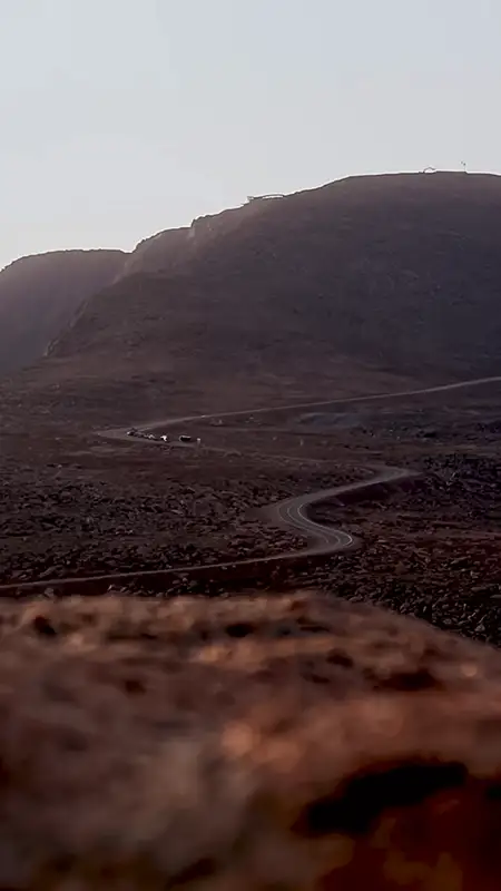 A desolate landscape with rolling brown hills and a winding path, under a muted sky.
