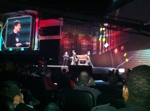 a stage with people moving around and people are sitting on chairs and looking at the stage