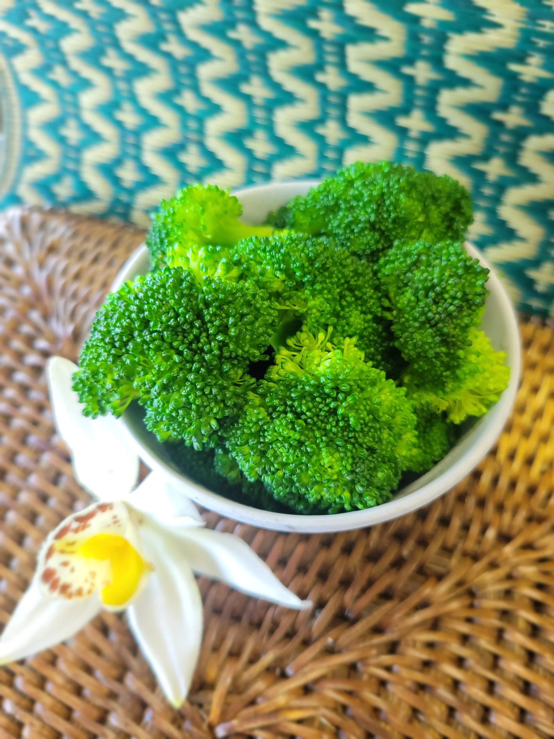 A white bowl filled with freshly steamed bright green broccoli florets.