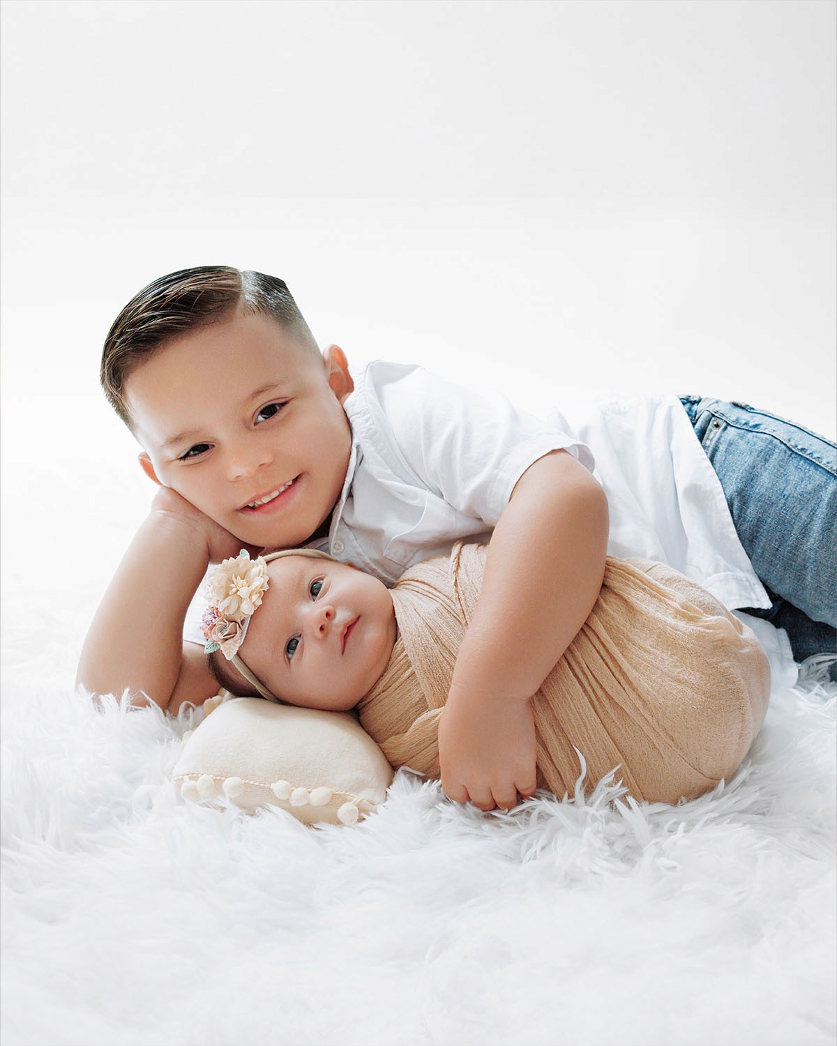 Sibling and newborn photo — sister gently hugging baby brother.
