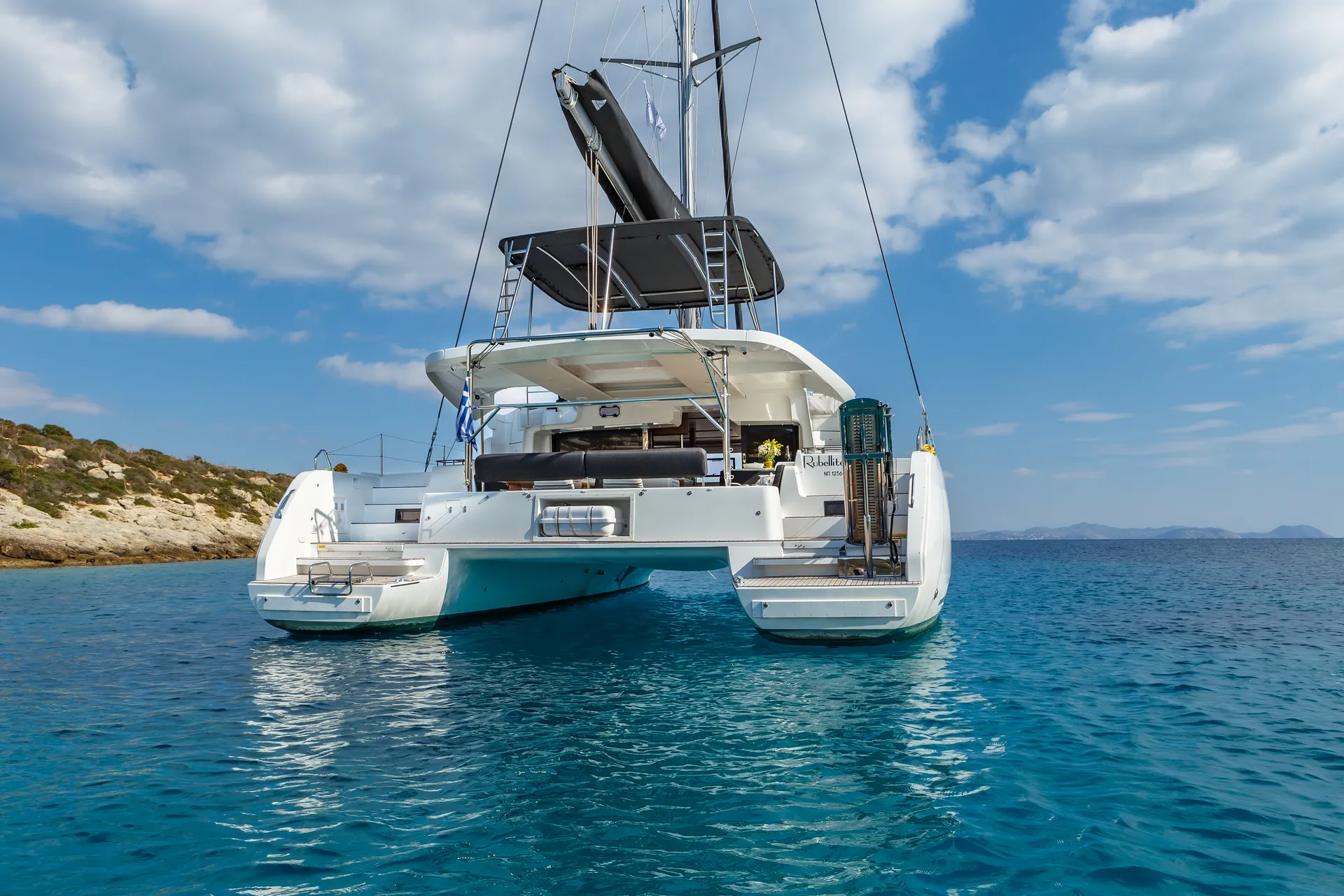 White Rock 36 speedboat with captain at helm cruising calm blue waters near Paros coastline with hills in background.
