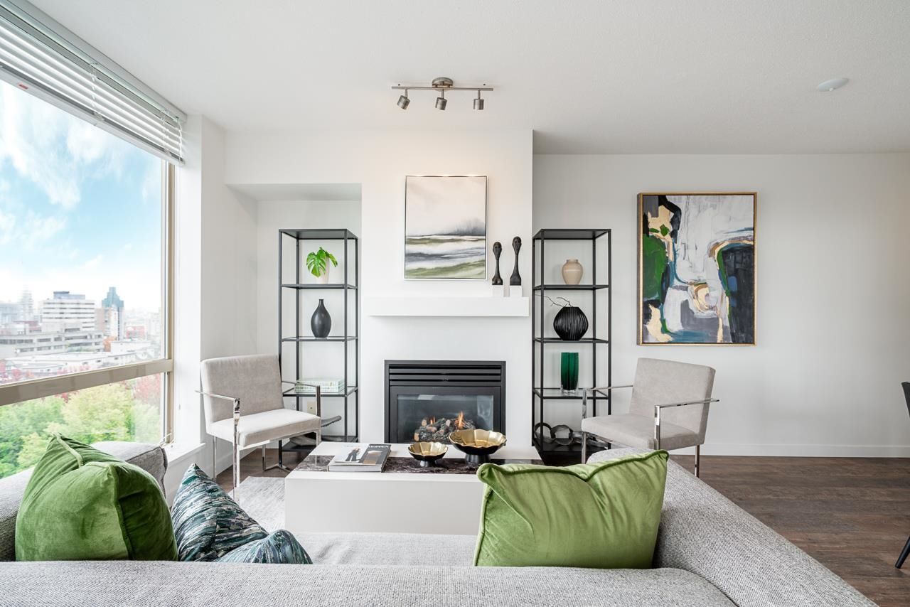 Bright modern living room with large windows, fireplace, and green accents. Artwork hangs on the wall.