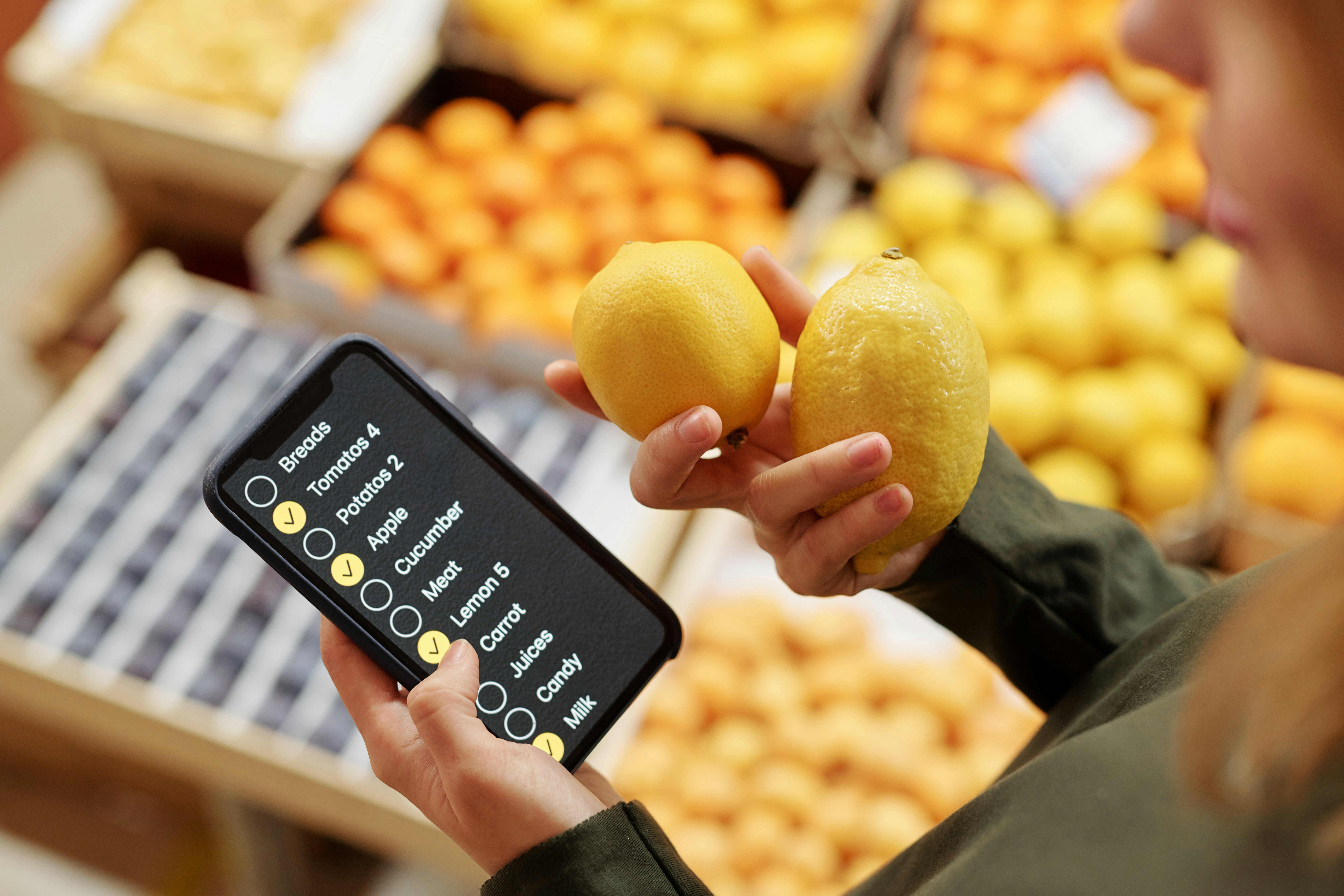 Person using a digital grocery list while shopping for lemons.