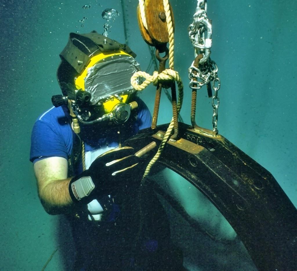 Historical profile image of a diver handling a submerged lifting arrangement.