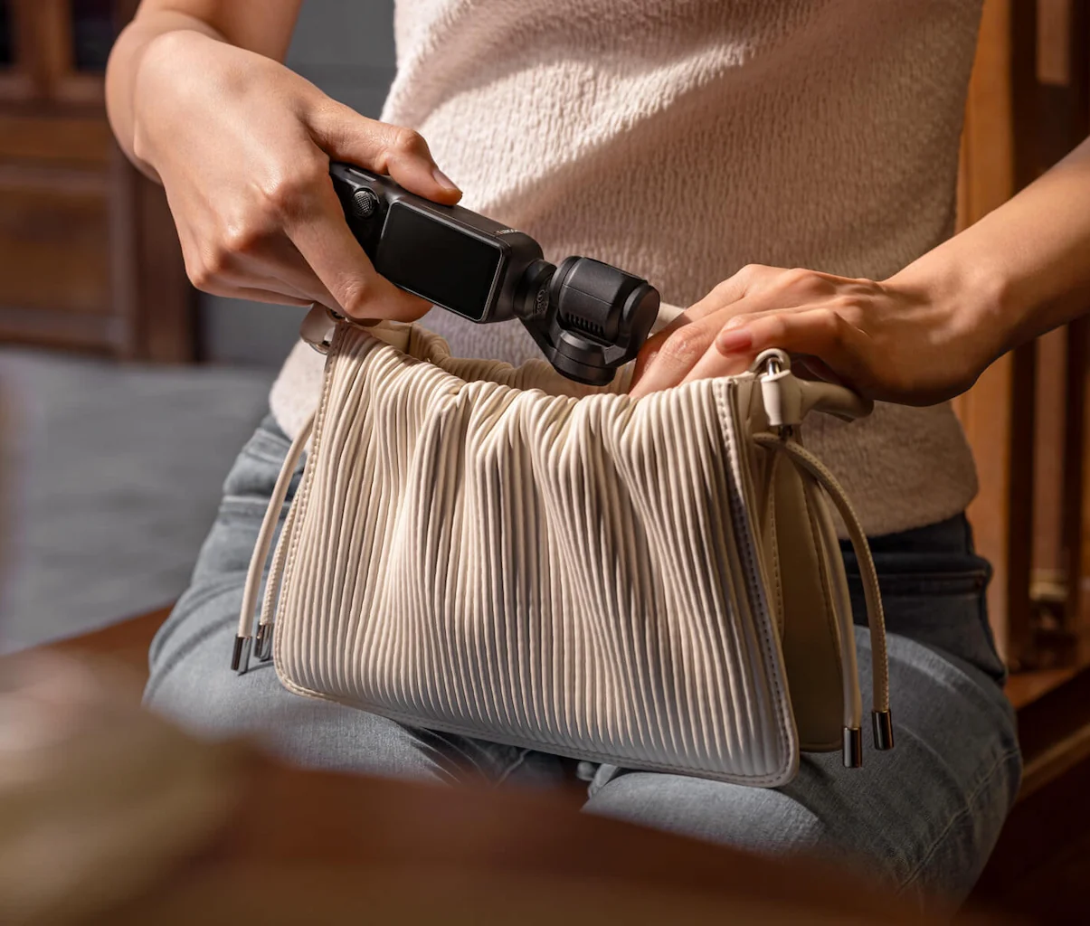 Person putting pocket camcorder into small bag
