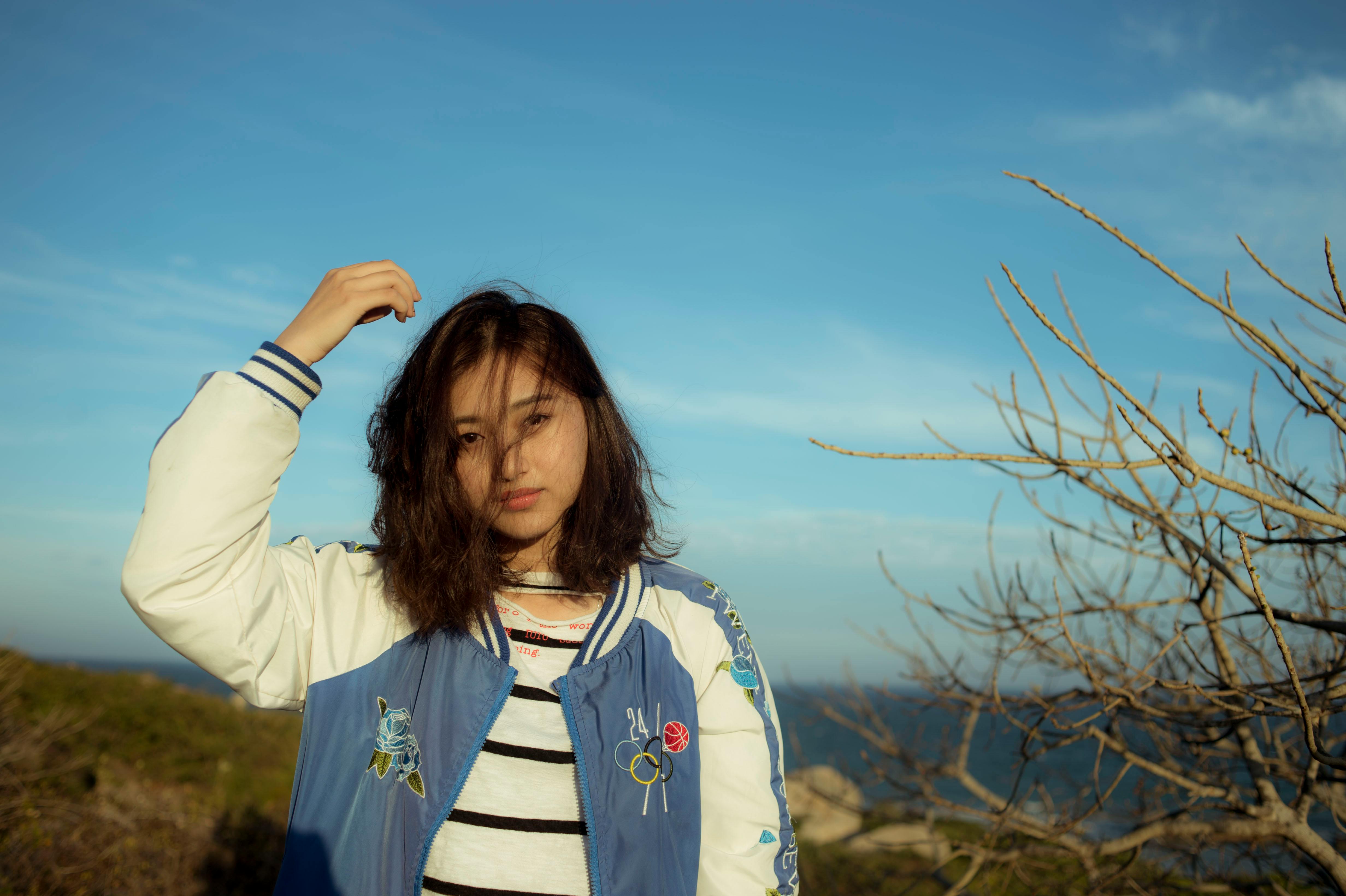 A young woman in a bomber jacket poses outdoors