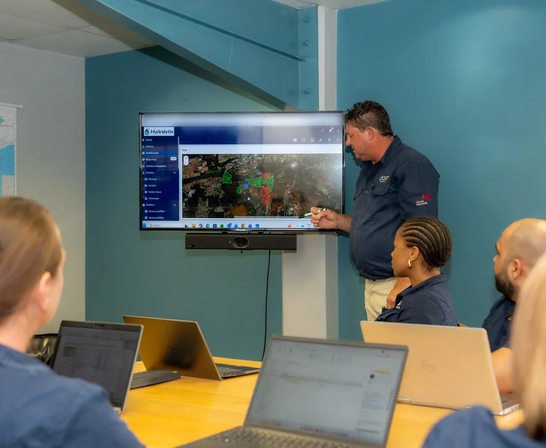 JOAT engineer presenting a Hydralytix network map to the team on a wall screen