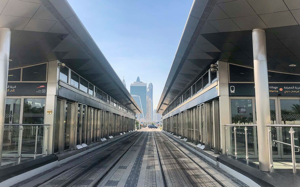 Walkway between two glass-windowed buildings in Al Sufouh: modern architecture, urban design.
