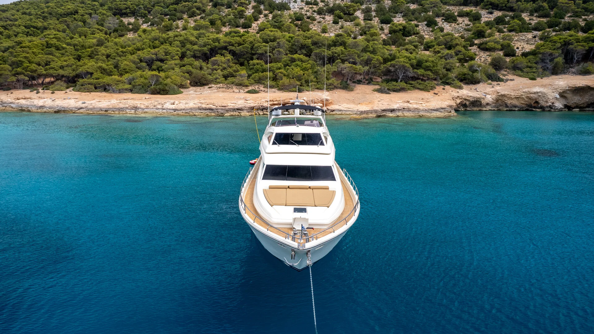 White Rock 36 speedboat with captain at helm cruising calm blue waters near Paros coastline with hills in background.