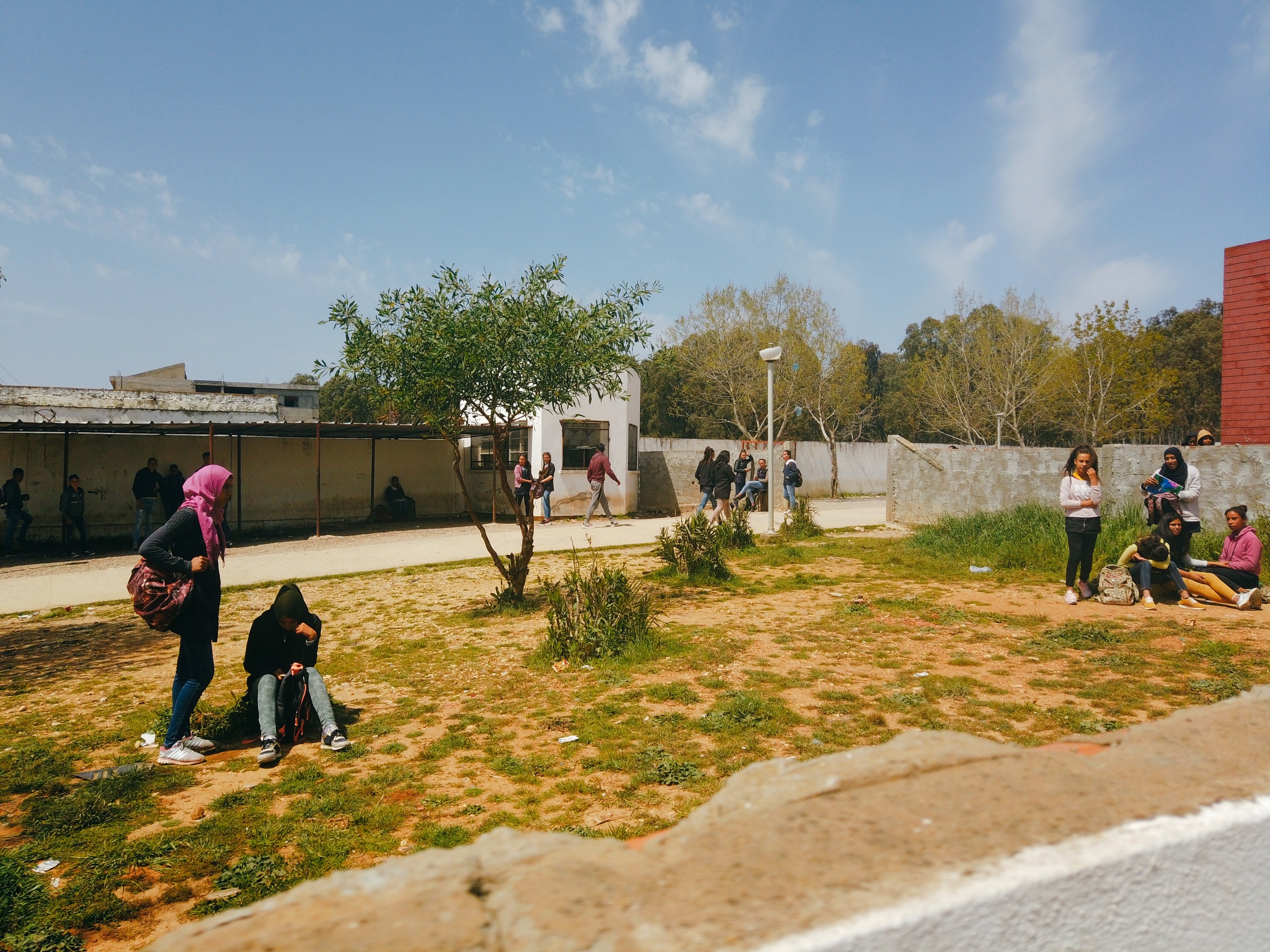 Scène de vie d'une cour d'école en Tunisie montrant des groupes d'enfants discutant entre eux