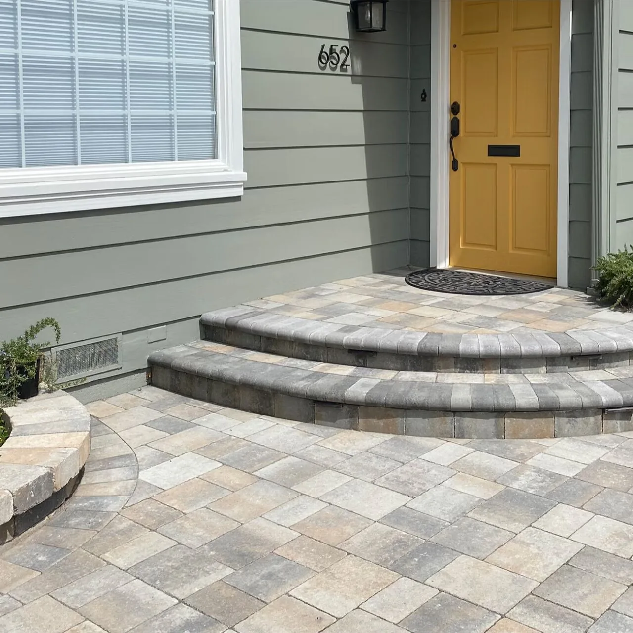 Rounded paved entry steps leading to a yellow front door.