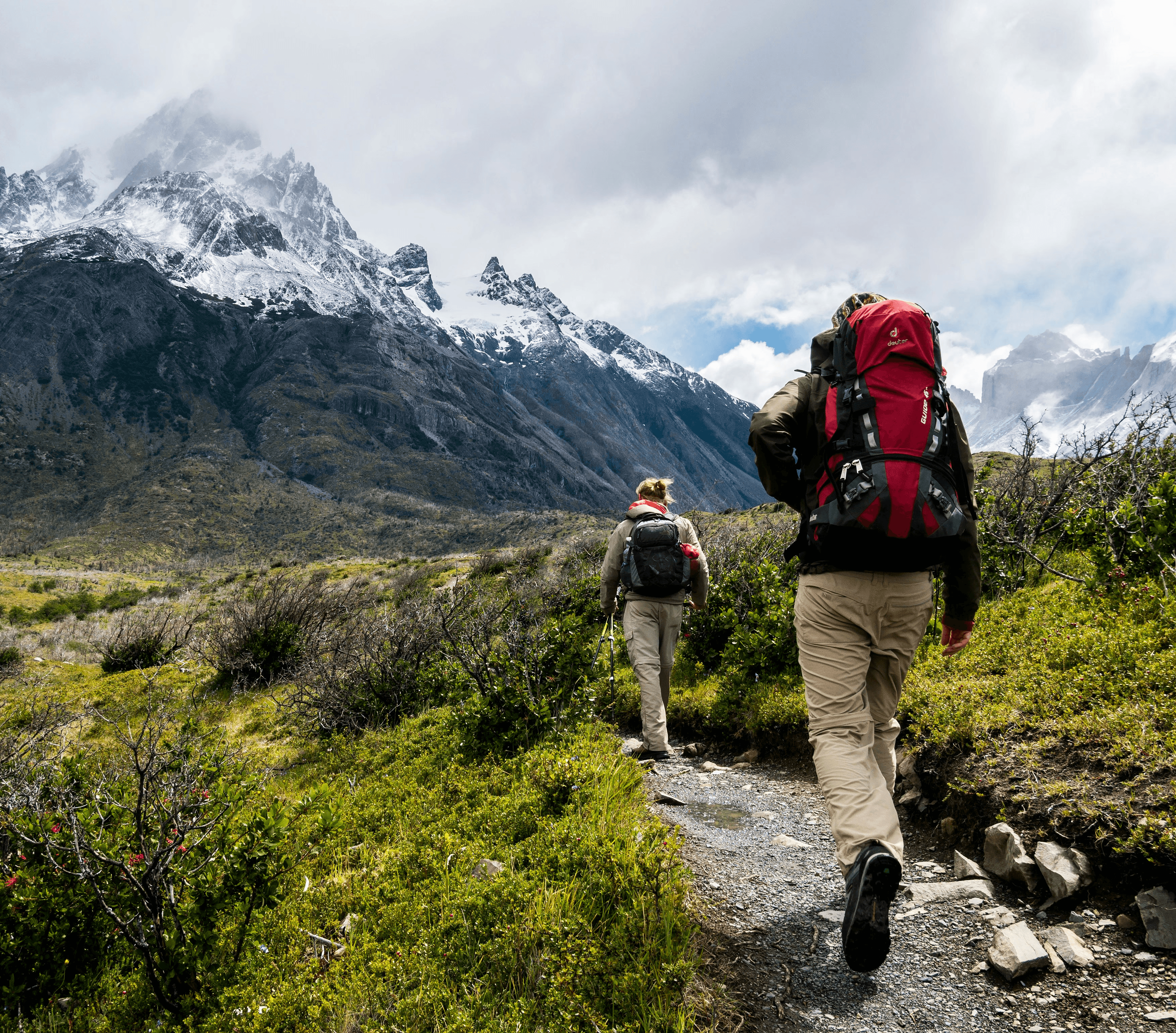 two person walking towards mountain covered with snow