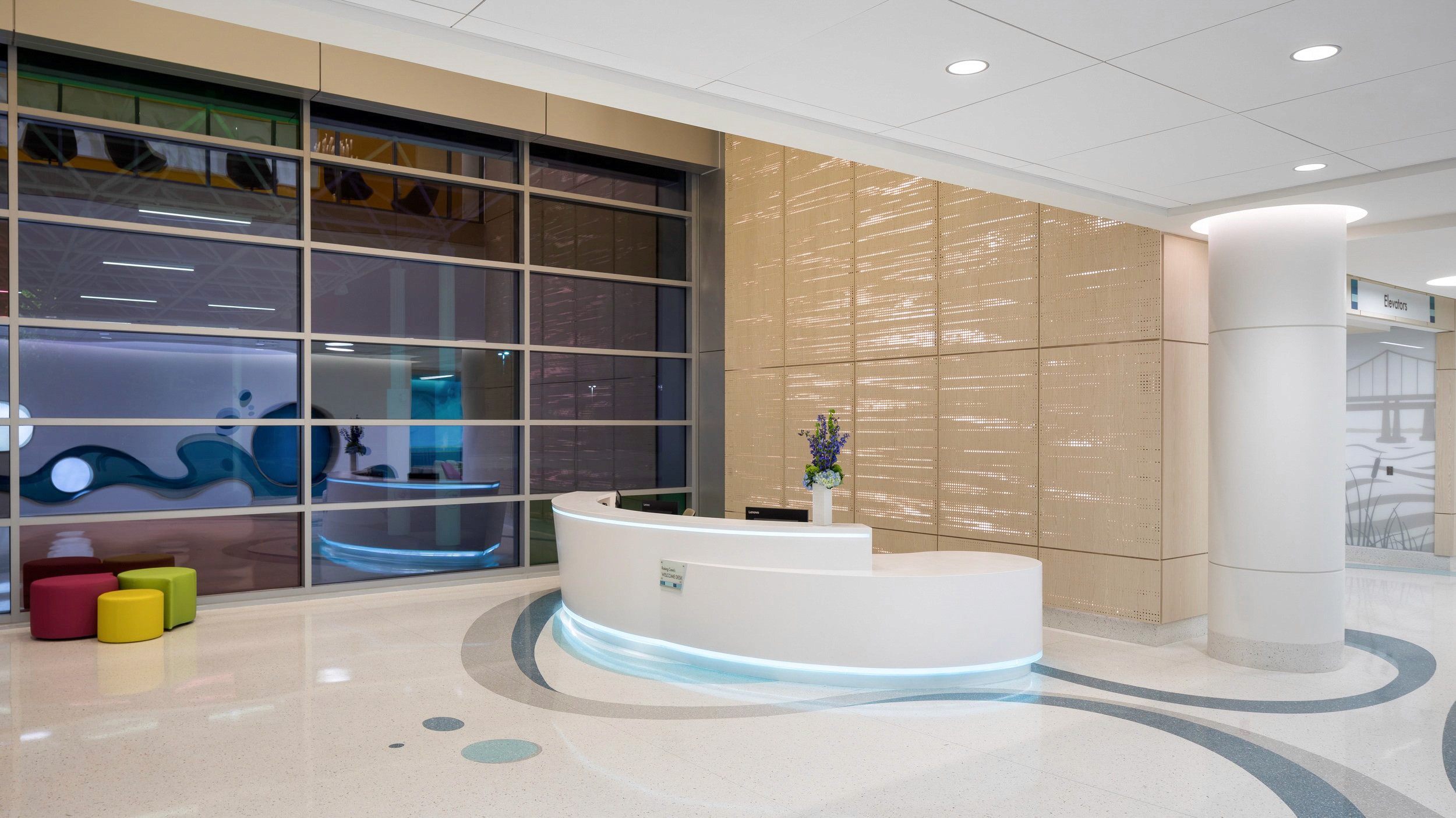 Modern reception desk with blue LED lighting and colorful stools.