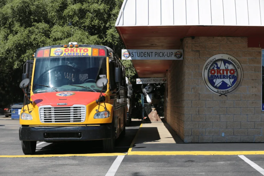 A pickup bus parked next to an Okito building. 