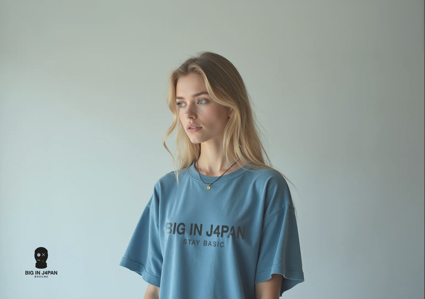 Bonita joven rubia con una camiseta azul descolorida con el logo de Big In Japan en el frente