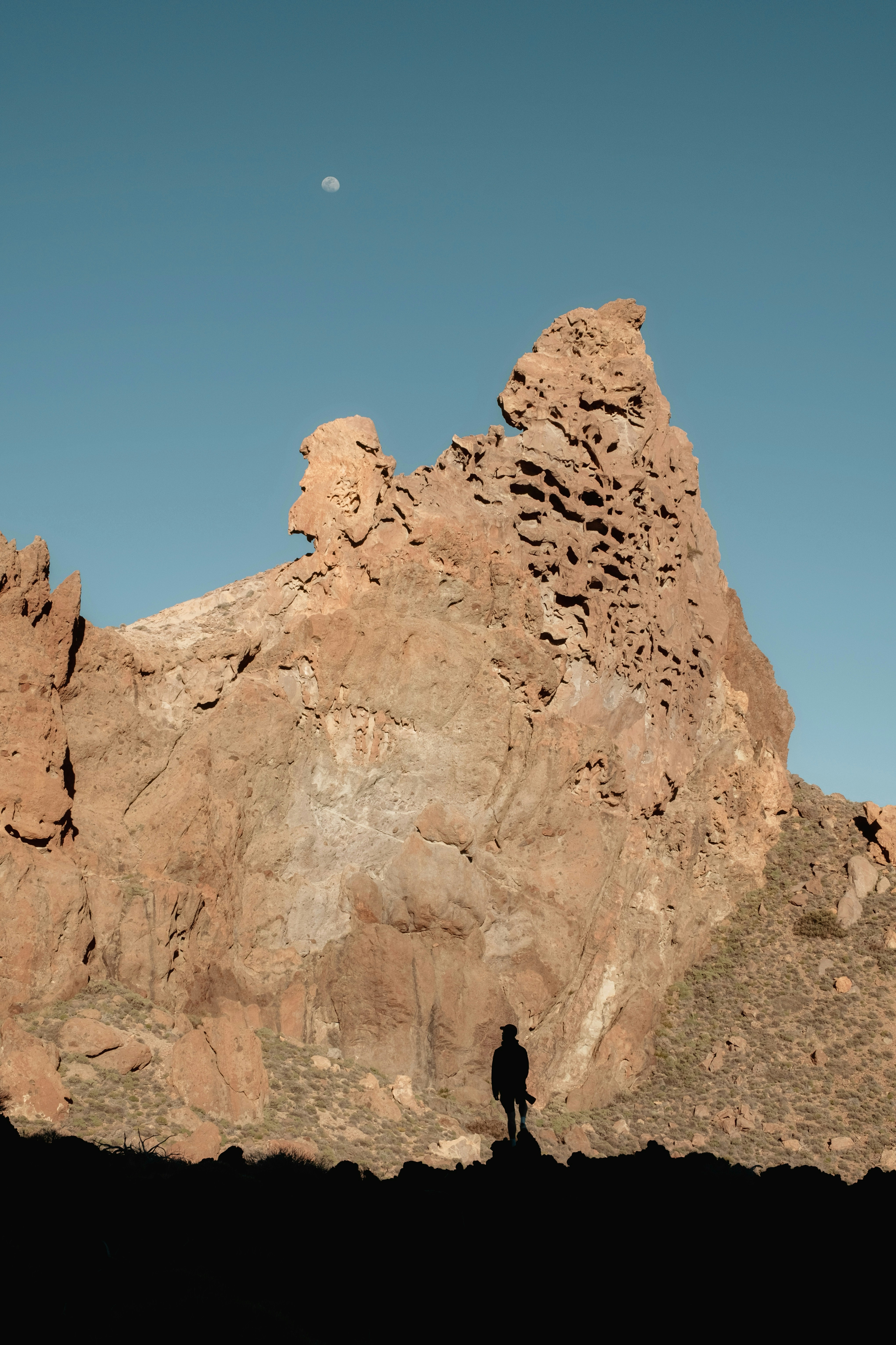 Silhouette of a person standing before a large rock formation