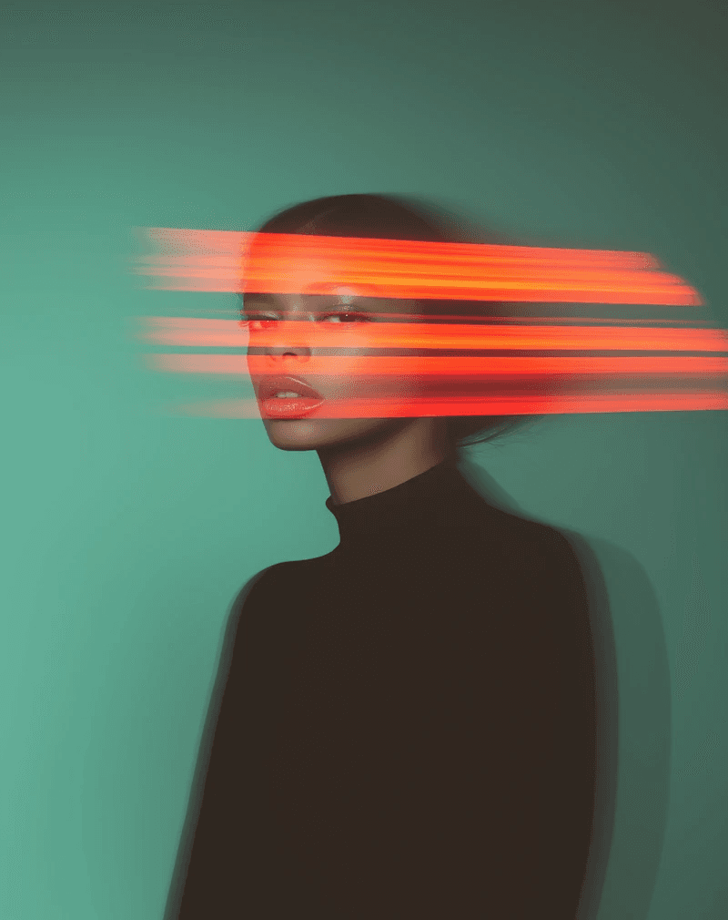 A woman in a black turtleneck poses against a teal background. Her face is partially obscured by horizontal red light streaks, creating a futuristic feel.