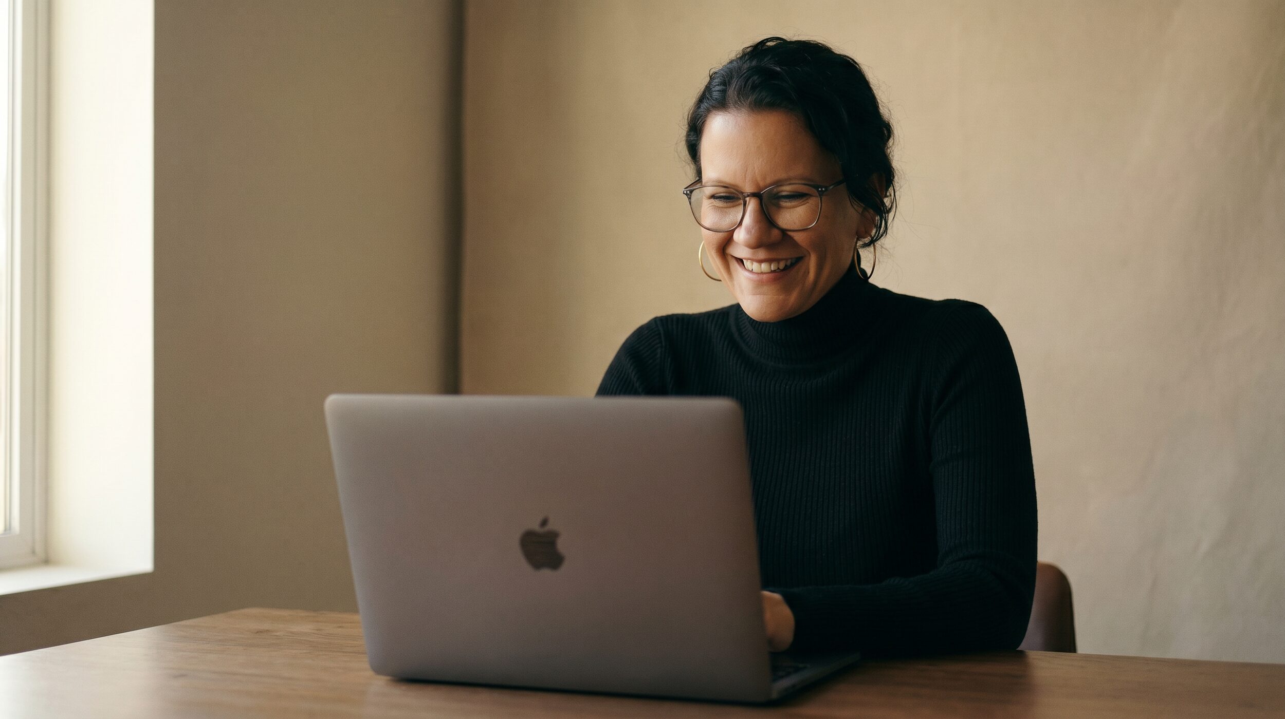 Frau schaut lachend auf Laptop