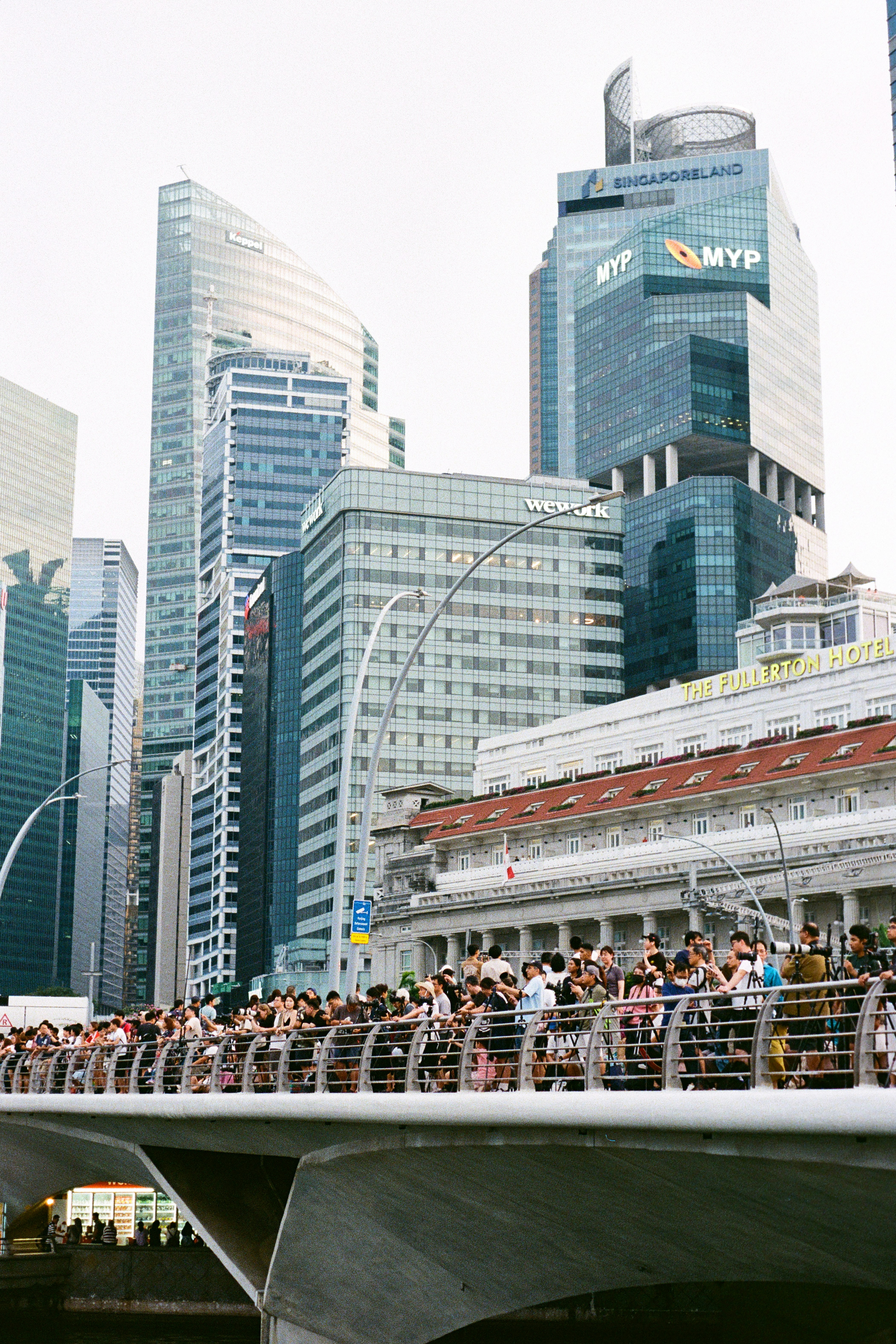 Skyscrapers tower over a bridge full of people.