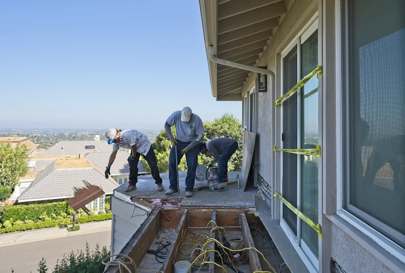 3 men demoing a second story deck overlooking an exclusive Newport Beach neighborhood below.