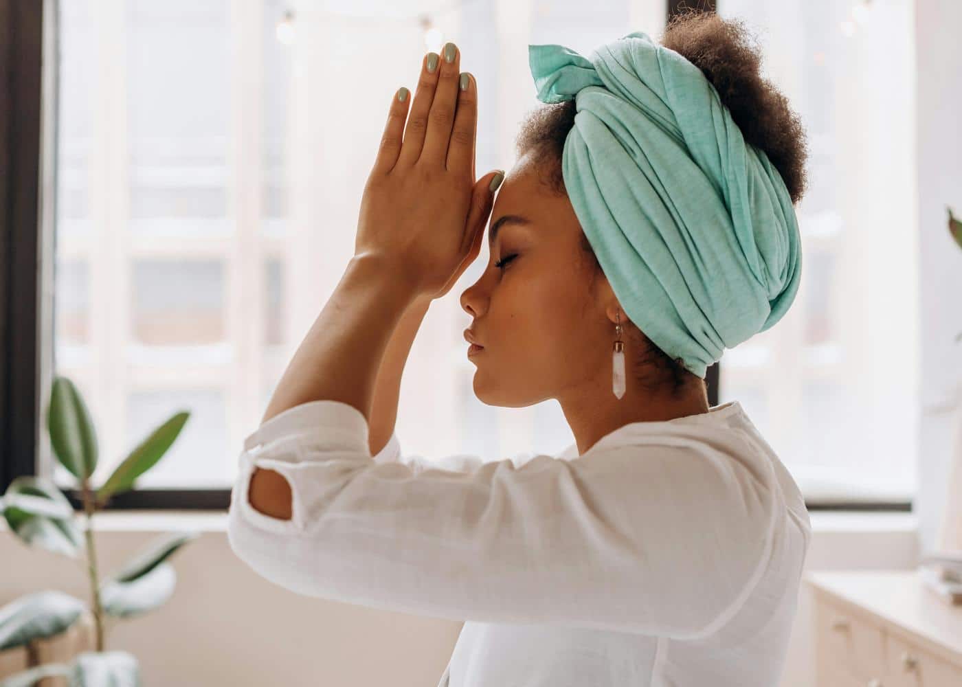 Morning meditation for beginners - Woman in a praying pose next to a window