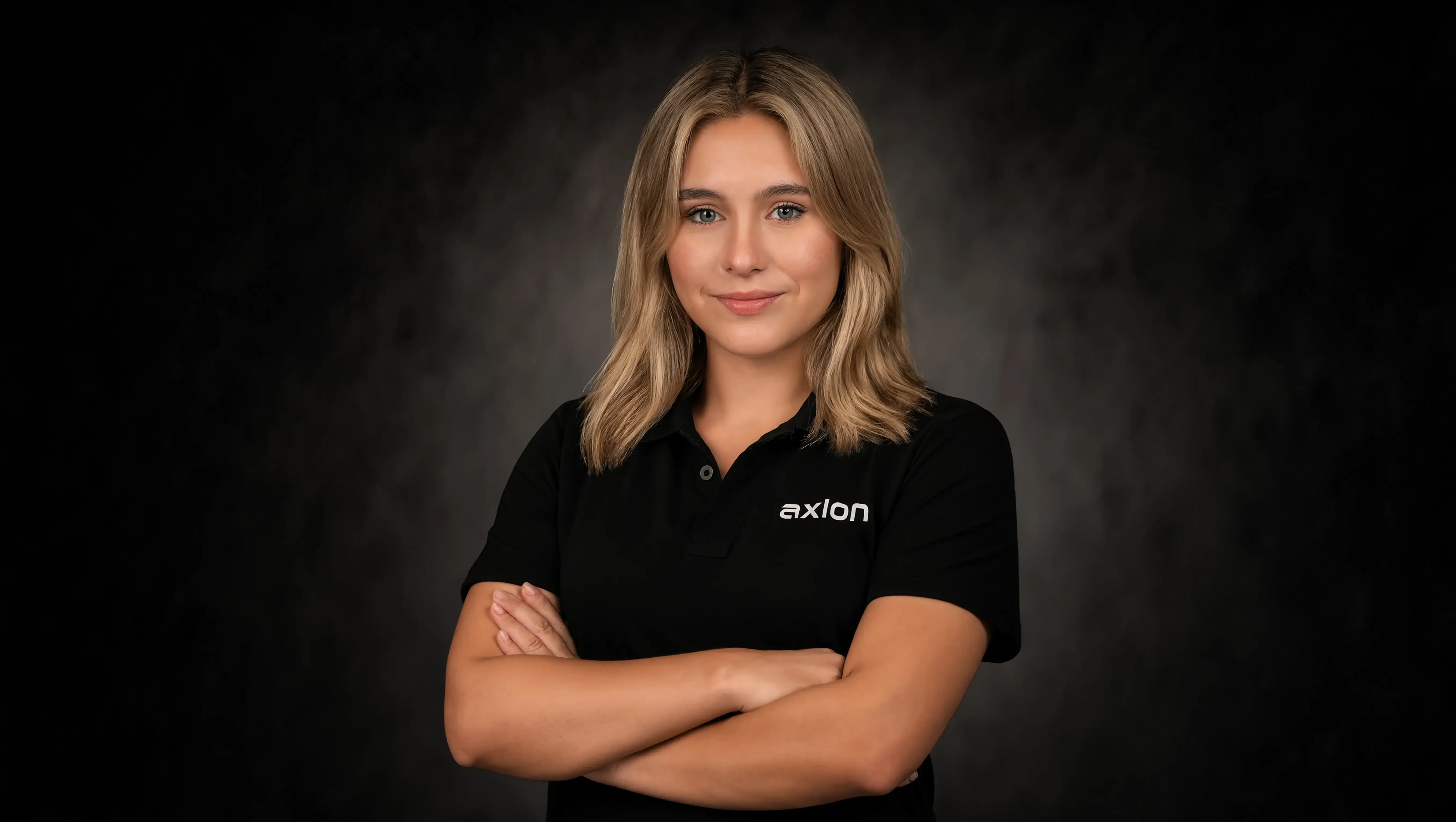 A girl posing with a black polo branded "Axion"