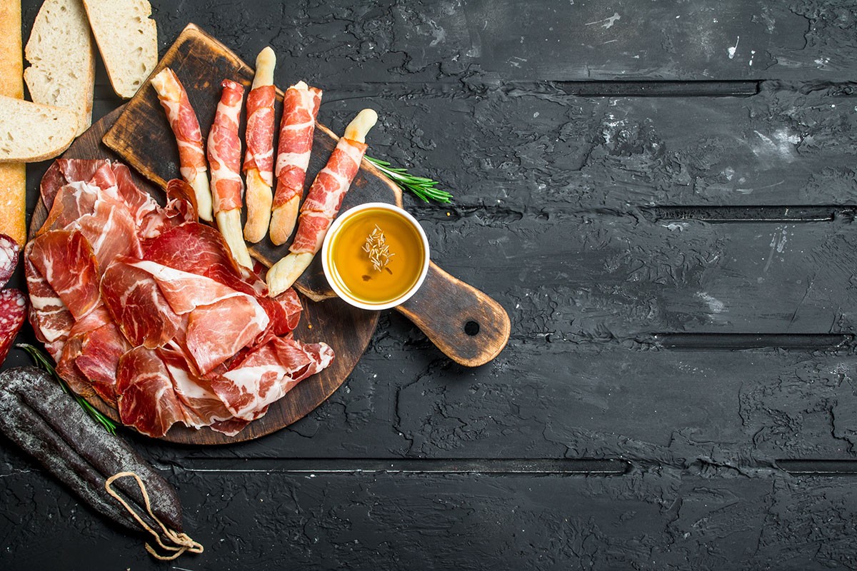 A woman with Porcellino Artisanal Meats holding a tray of sliced meats.