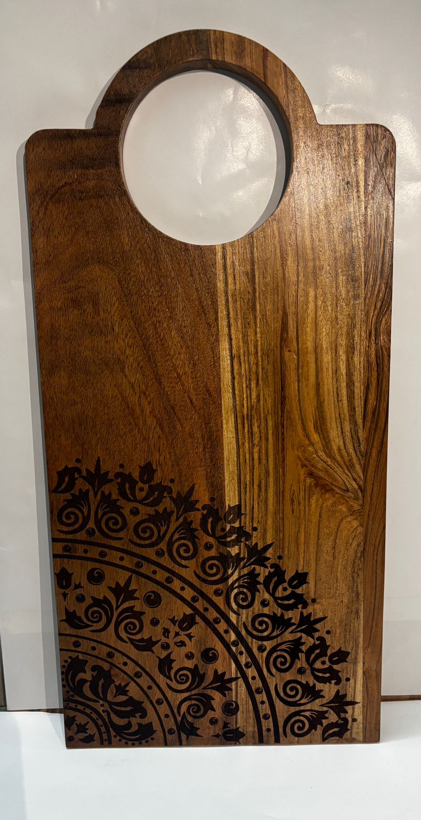 Handcrafted wooden serving board with round handle and floral pattern