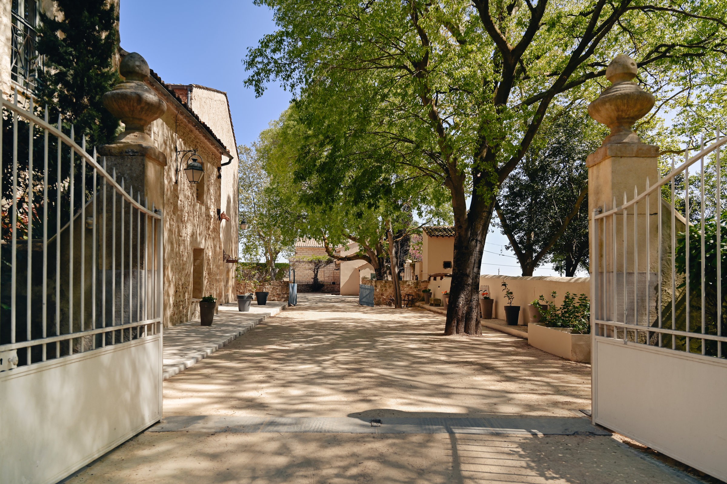 Entrée d'un mas ancien rénové par Karbone Architectes, agence d'architecture à Montpellier spécialisée dans la rénovation de maisons en pierre, mas languedociens, demeures de caractère, domaines viticoles et bâtiments patrimoniaux. Réhabilitation complète d'un patrimoine ancien avec restauration des façades, conservation des éléments architecturaux d'origine, valorisation des espaces extérieurs, intégration paysagère et mise en valeur des matériaux traditionnels. Architecte expert en rénovation de bâtiments anciens, maisons de campagne, bastides, granges et propriétés de caractère dans l'Hérault, le Gard et l'ensemble de l'Occitanie. Projet de rénovation sur mesure conciliant authenticité, confort contemporain, performance énergétique, architecture durable et respect de l'histoire du lieu. Aménagement des accès, cours intérieures, jardins méditerranéens et espaces de réception extérieurs pour révéler tout le potentiel du patrimoine bâti.