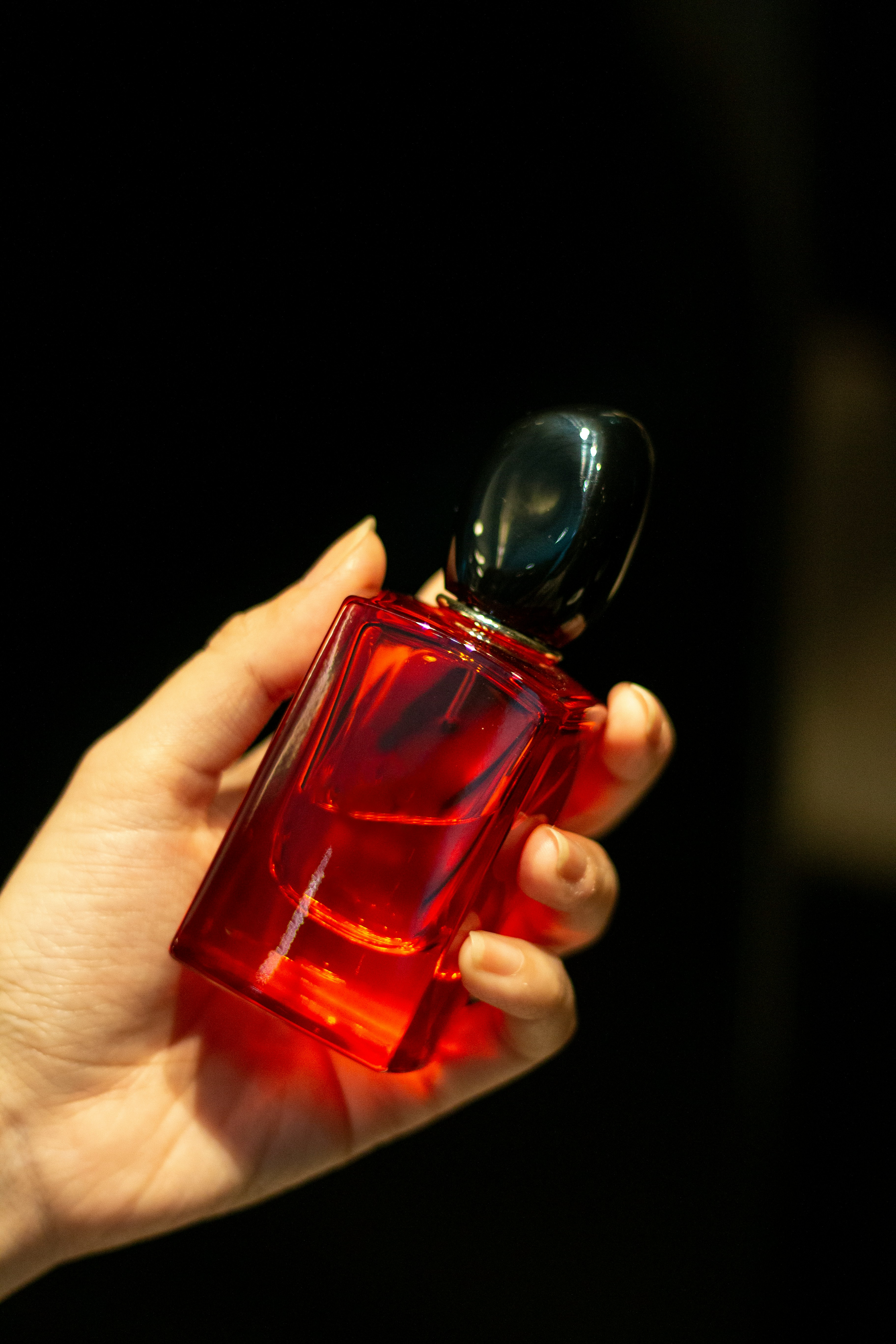 a person holding a red bottle of perfume