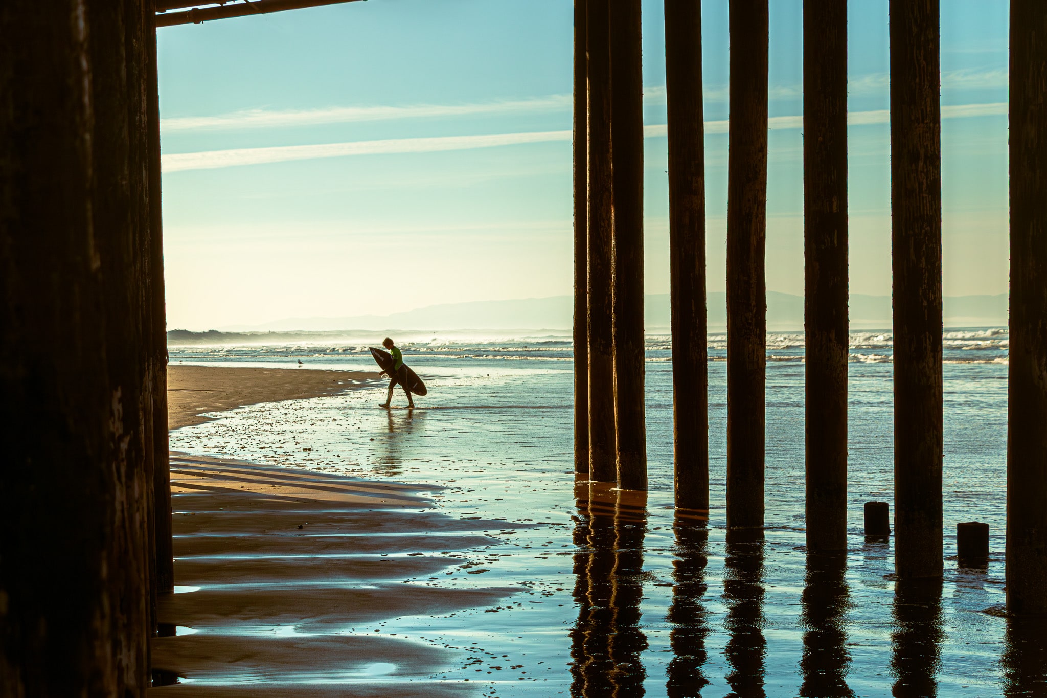 surfer walking under the boardwalk
