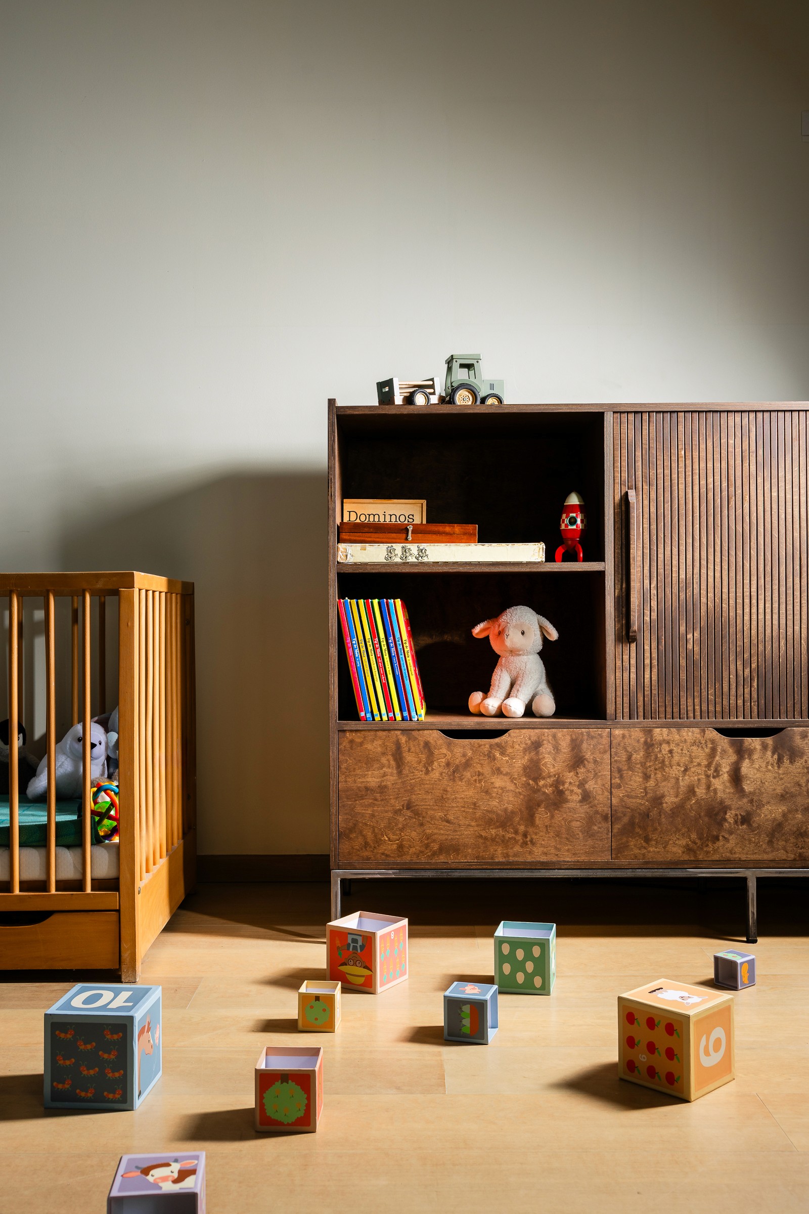 een tv-meubel met een roldeur die gesloten kan worden zodat de tv niet meer zichtbaar is in een woonkamer met kinderspeelgoed