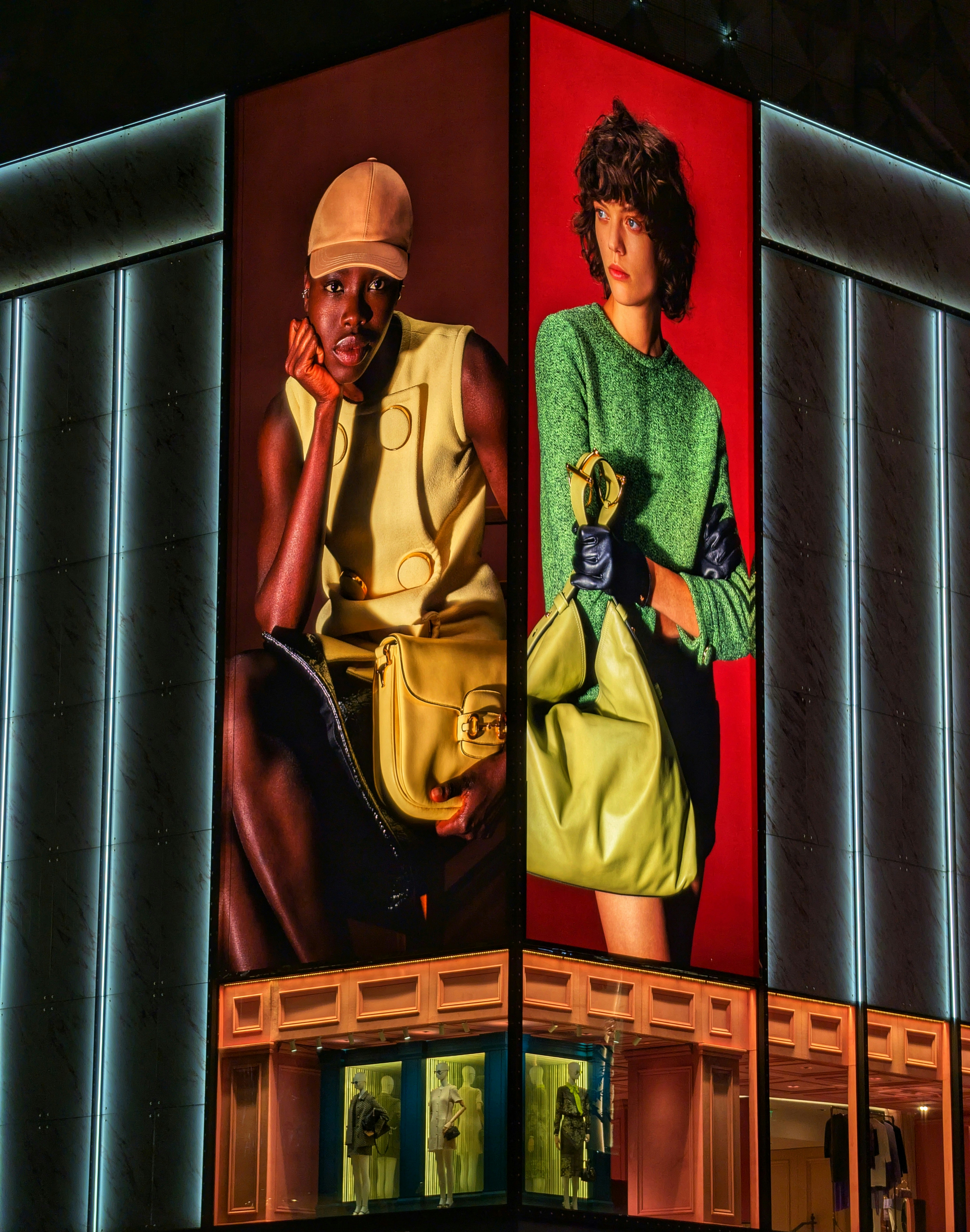 Two women modeling fashion on a building facade.