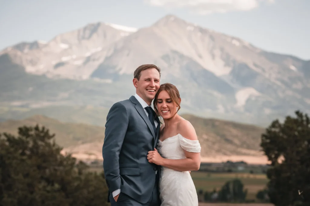 Newlyweds embracing with a mountain peak behind them
