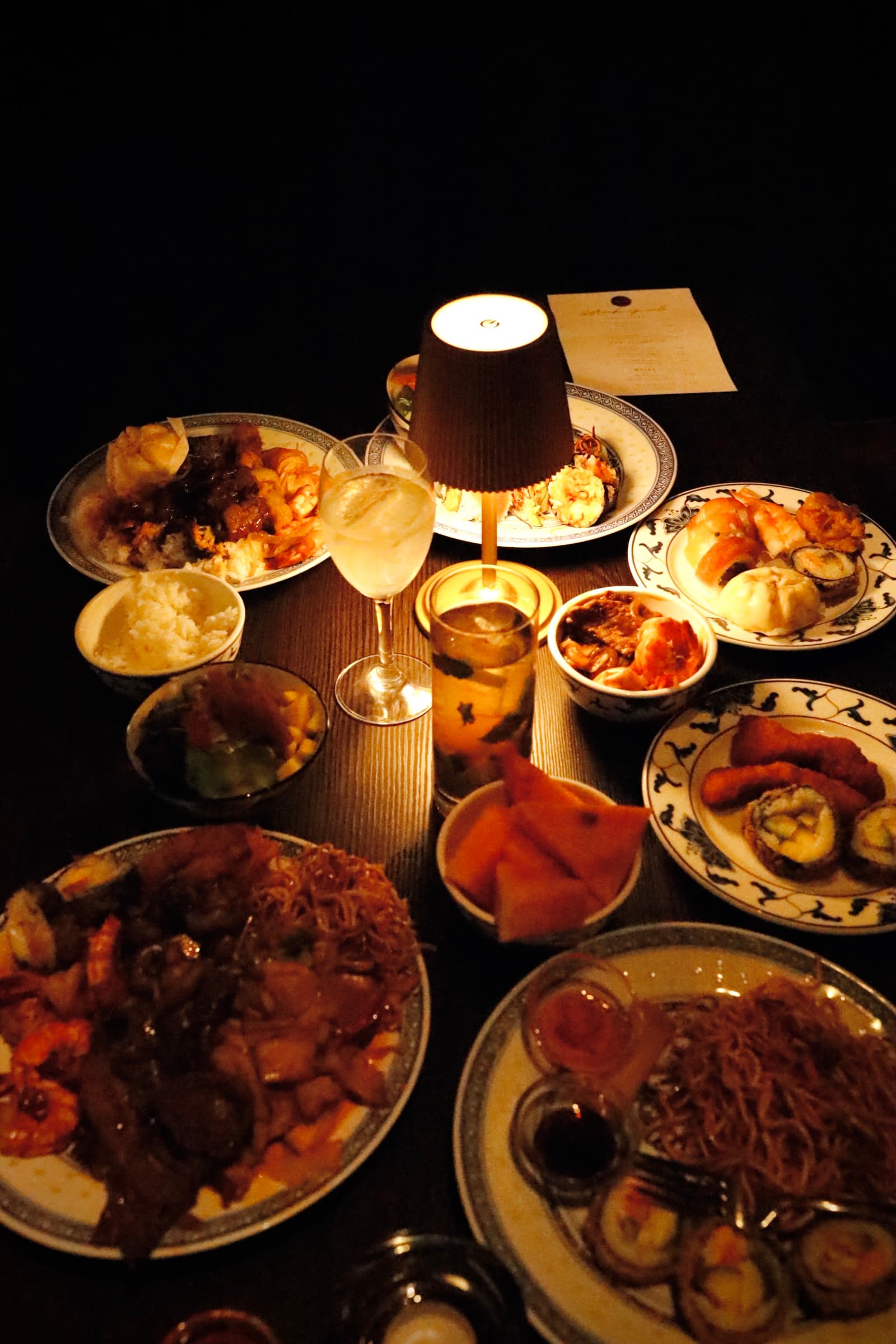 Reichhaltiges Abendessen mit verschiedenen asiatischen Gerichten, serviert auf einem Tisch im Dunkeln