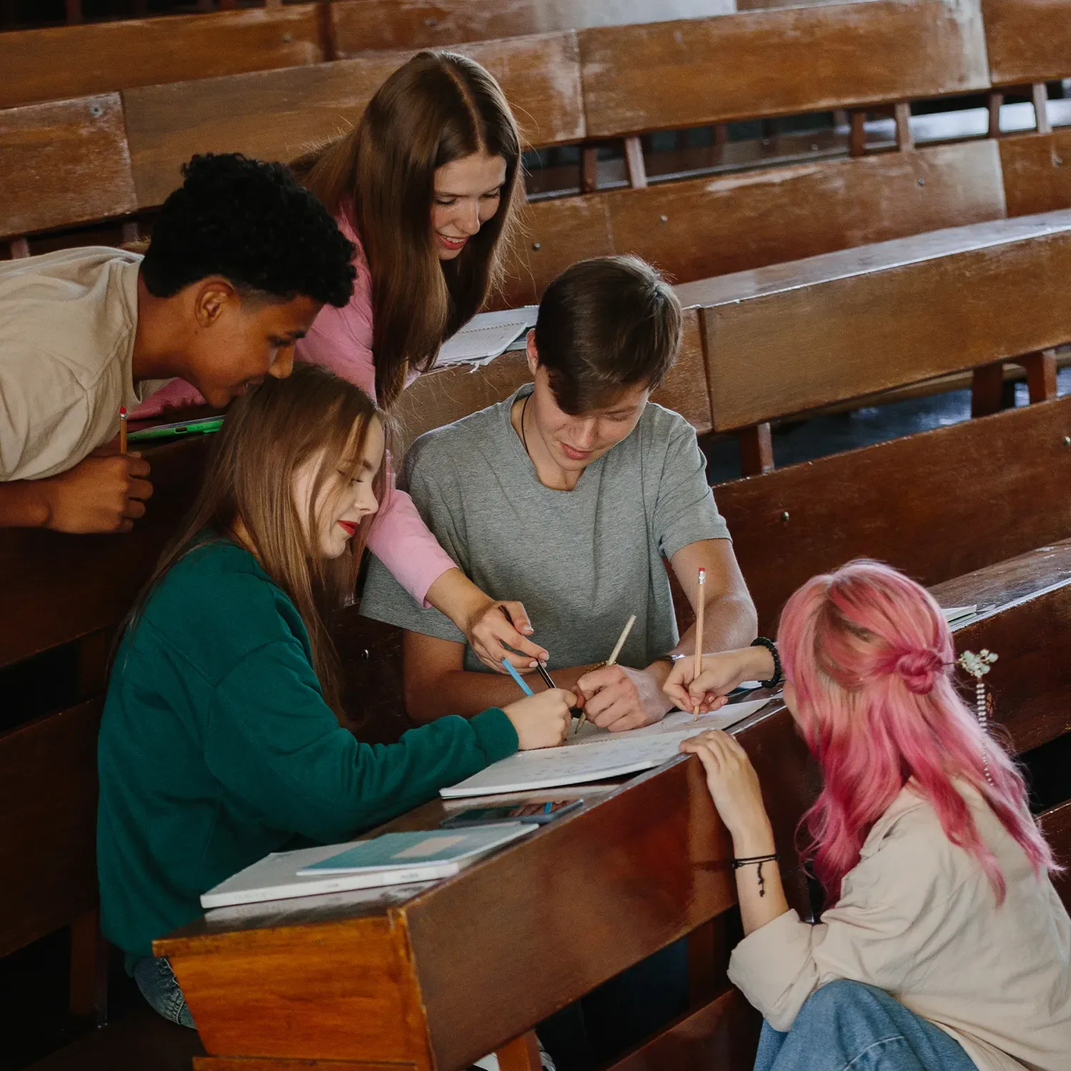 Skupina studentů při společné práci v lavici. Podpora vzdělání a talentů je investicí do budoucnosti.