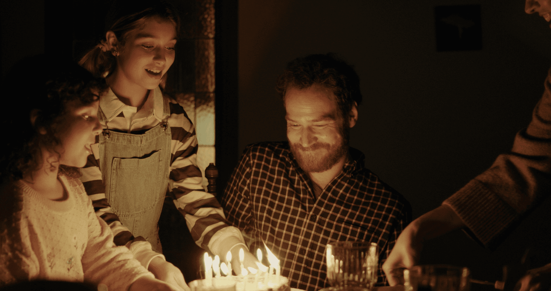 View of the French countryside through a stone villa’s open living room, with sofas and trees framing the scene