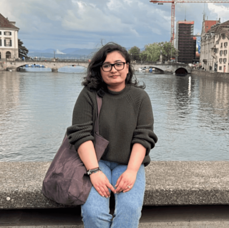 A thoughtful young person with dark hair gazes to the side, captured in soft black and white lighting.