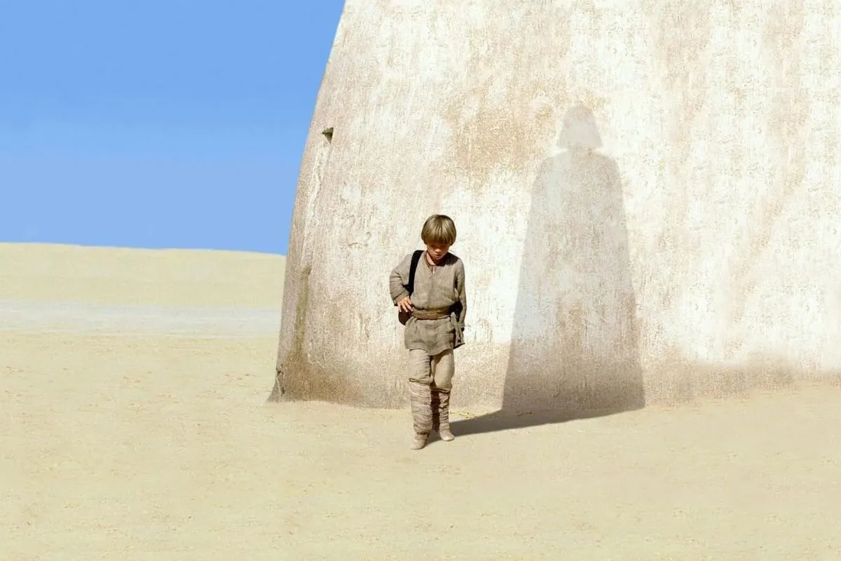 Promotional image from 'The Phantom Menace' depicting young Anakin Skywalker with the shadow of Darth Vader behind him. 
