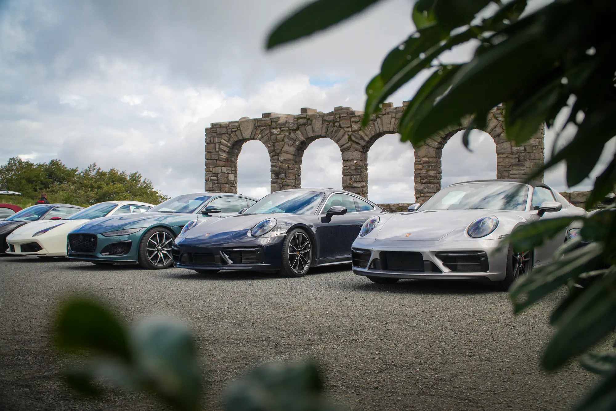 Porsche 911 et voitures de sport garées devant de vieilles arches en pierre
