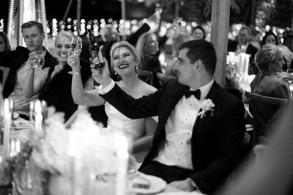 Bride and groom cheering drinks during speeches at their reception