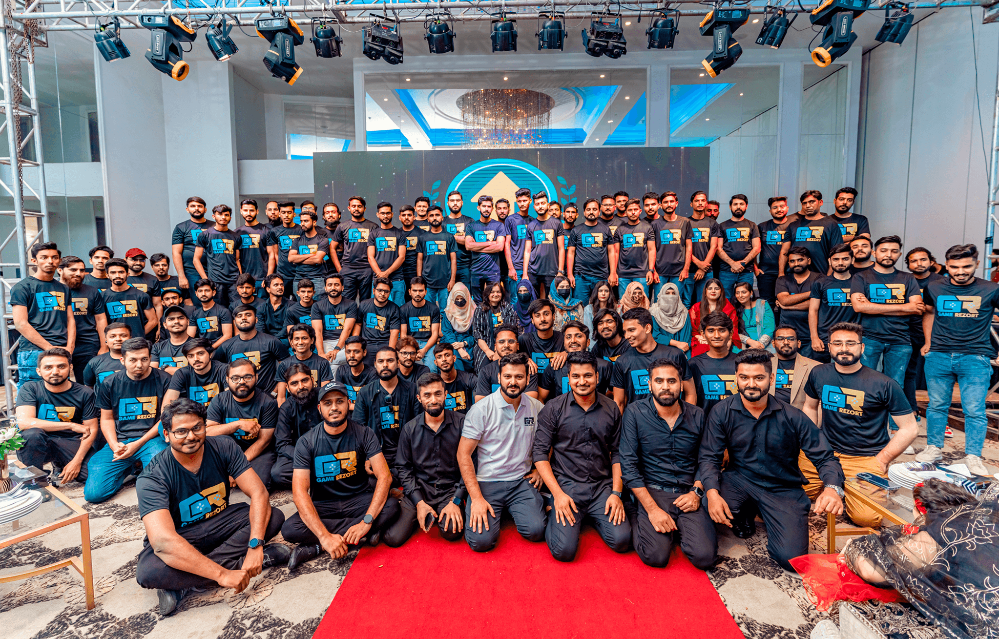three men sitting while using laptops and watching man beside whiteboard