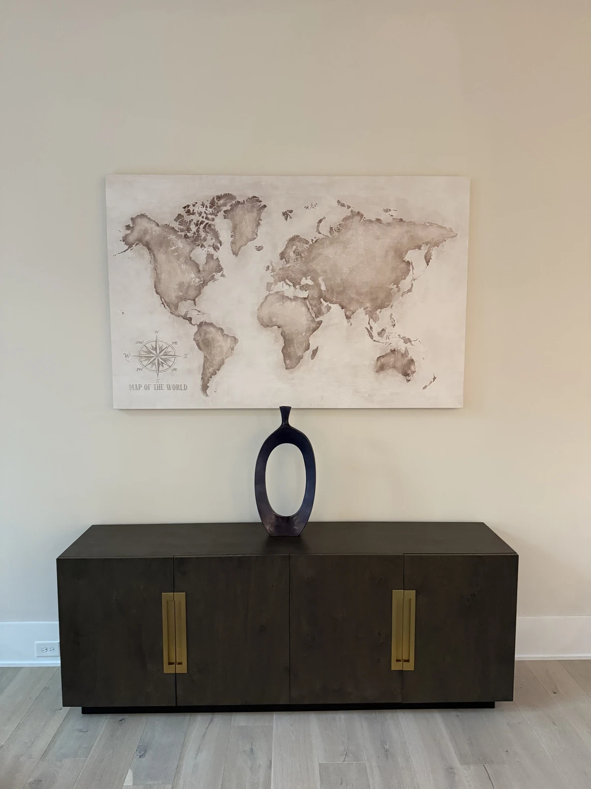 World-map canvas installed above a dark wood console with a single decorative vase.