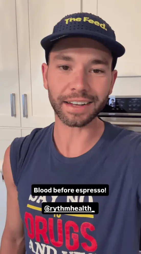 Man speaking to camera indoors with text overlay “Blood before espresso! @rythmhealth.”
