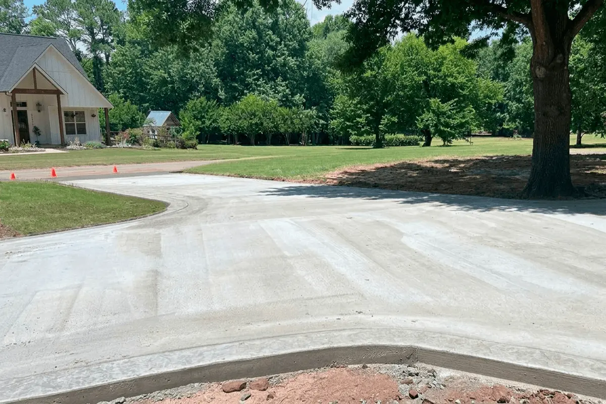 Newly built concrete driveway in front of a house with a spacious garden.