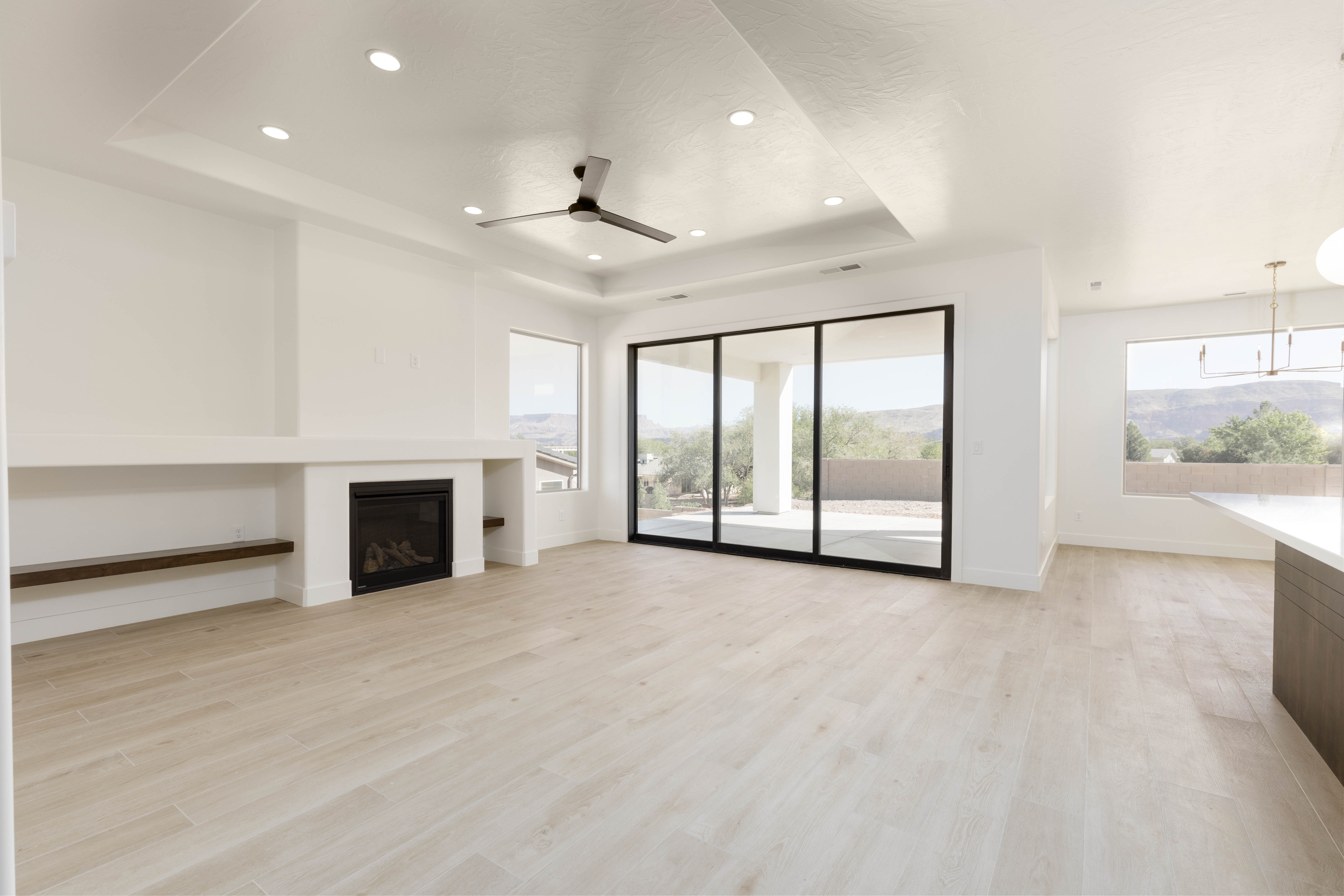Modern living room in The Meridian new construction home in Hurricane Utah featuring a contemporary fireplace and tray ceiling design.