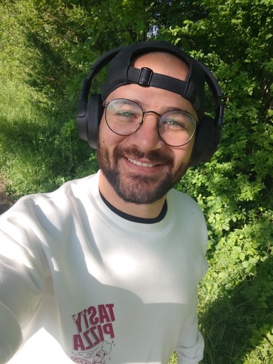 Man smiing with headphones on while taking a selfie