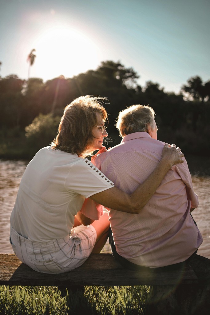 Loving moment between grandmother and granddaughter embracing outdoors with lush greenery, representing family support in NDIS aged care