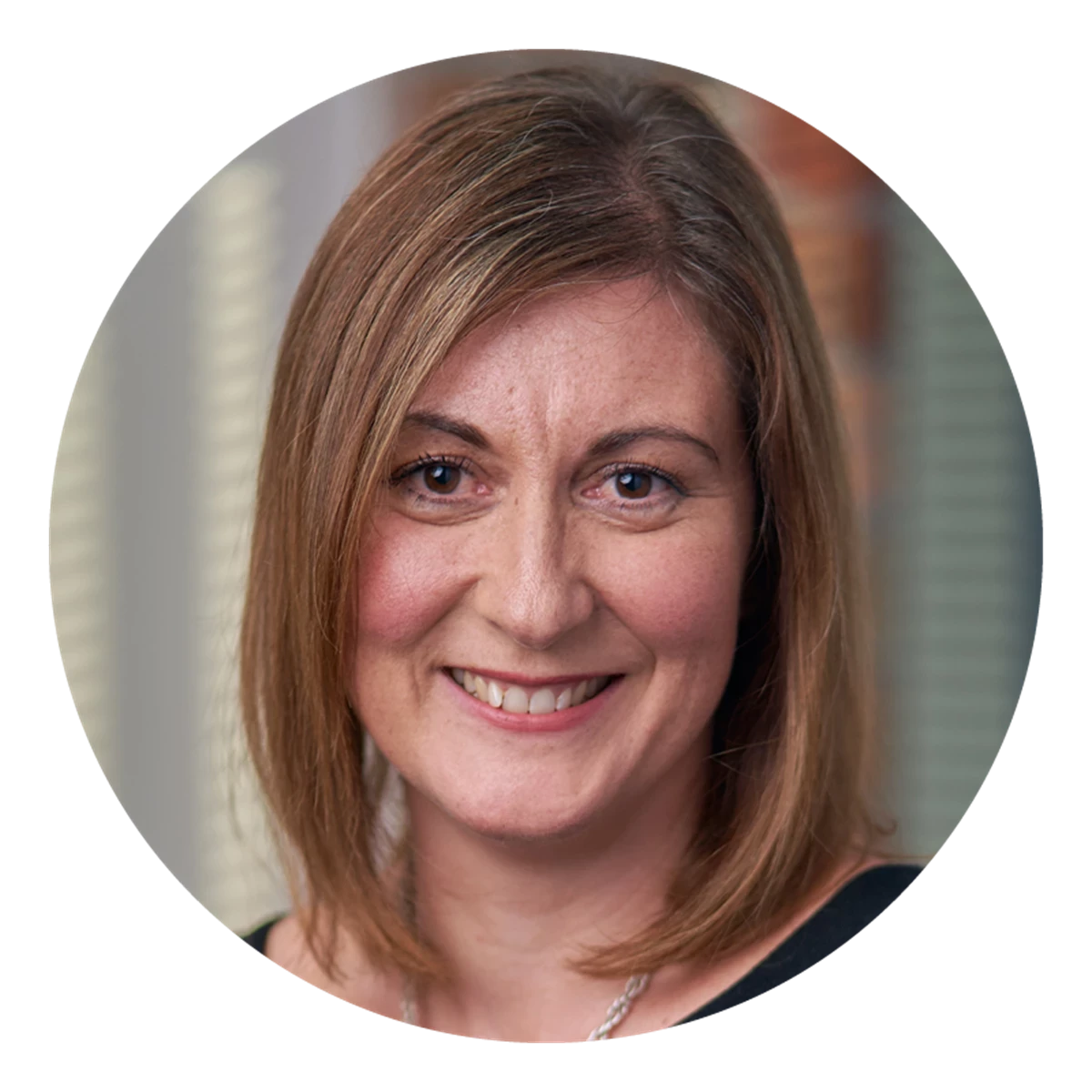 A circular portrait shows a person with shoulder‑length light brown hair indoors. Vertical window blinds and natural light form the background.
